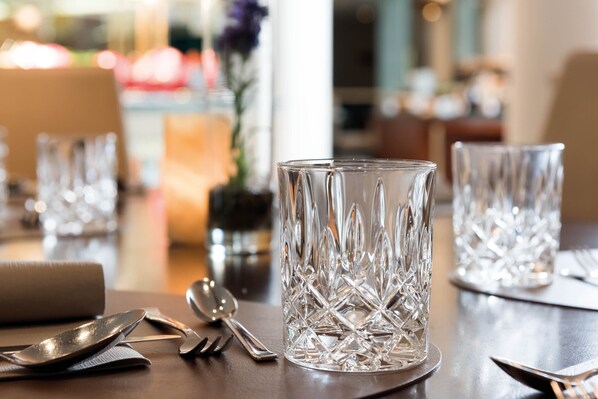 Une table à manger avec un centre de table en verre transparent, des couverts en argent et une serviette.