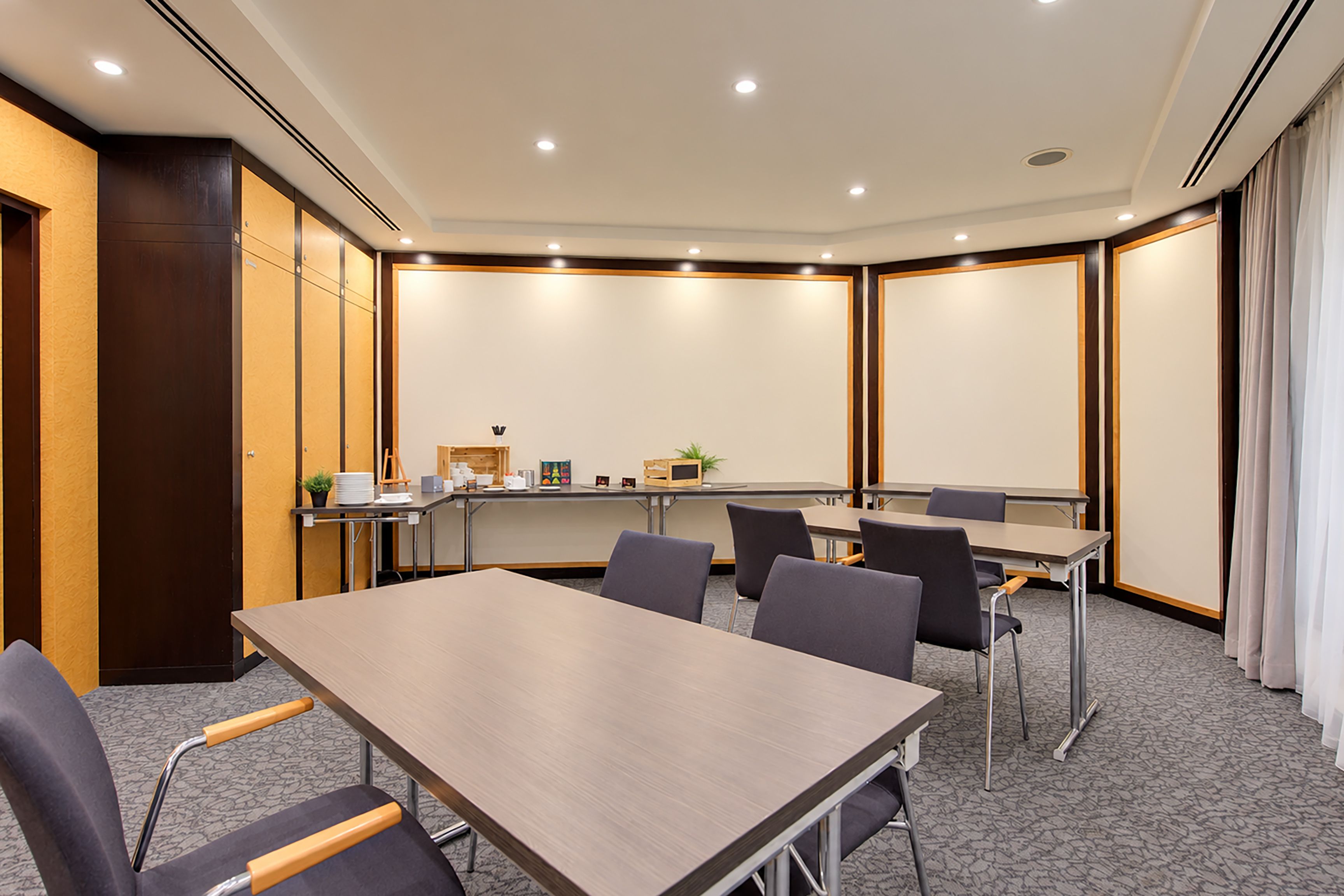 Un salón de conferencias con una larga mesa, sillas, una pizarra y una pequeña planta.