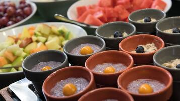 Ein Buffet mit verschiedenen Speisen, darunter Früchte, Pudding und Wassermelone.