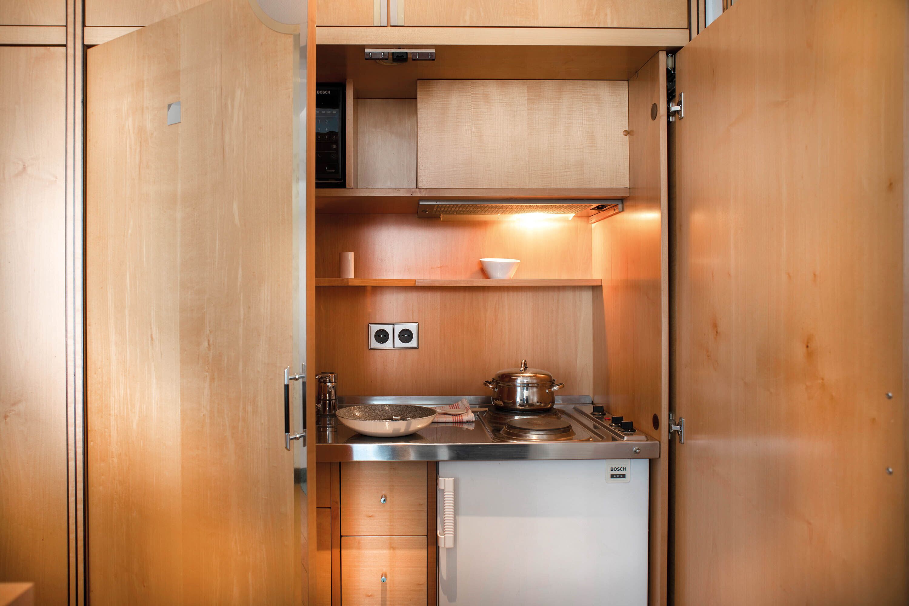 A compact kitchenette with a Bosch stove, a small sink, and a microwave.
