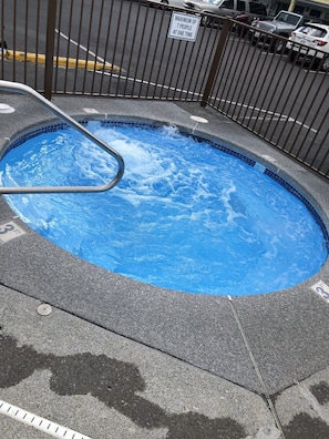 A swimming pool with a metal ladder, surrounded by a fence with a sign indicating a maximum of 7 people at one time.