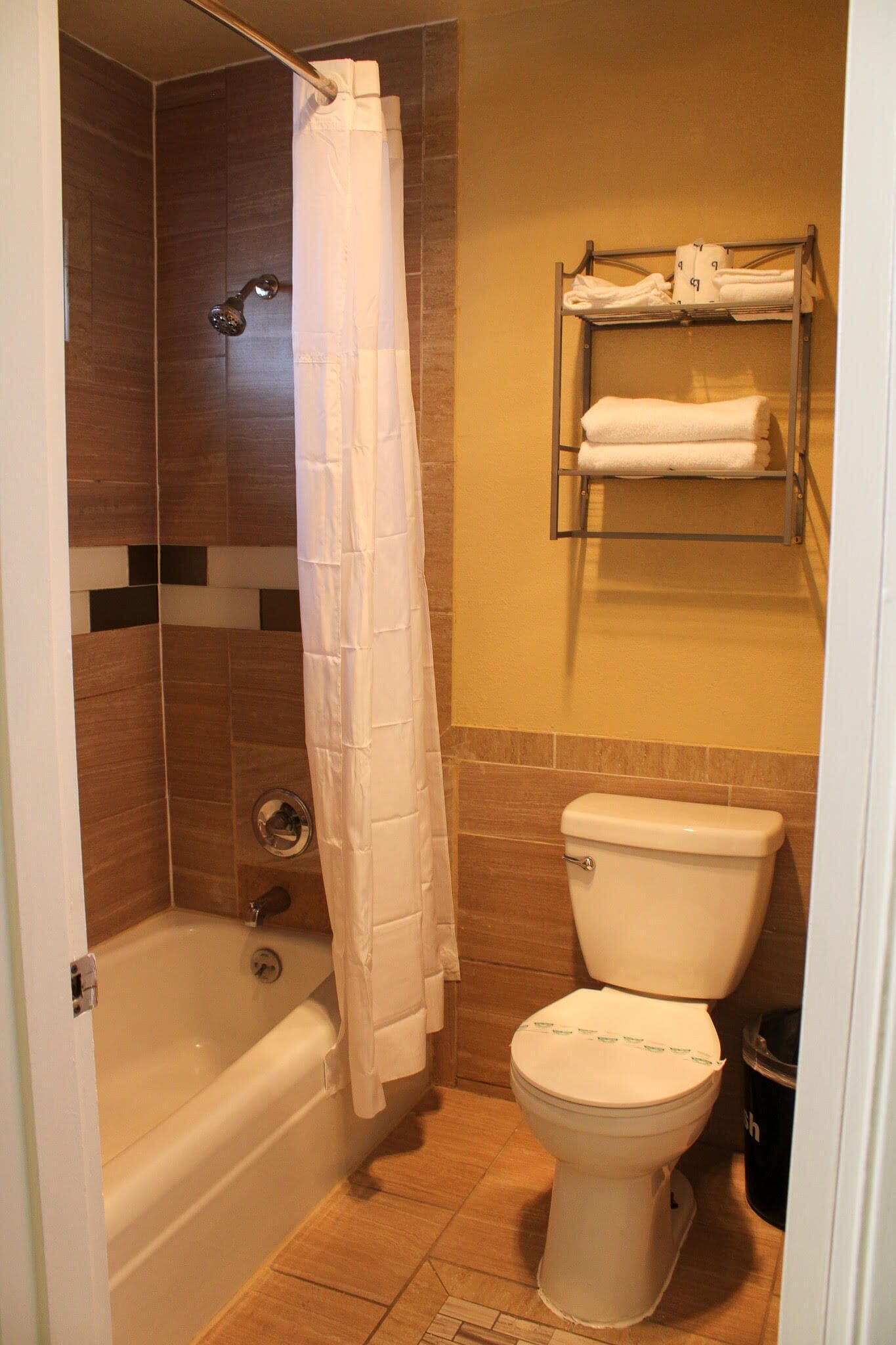 Un baño con bañera, inodoro, cortina de ducha y toallero con toallas.