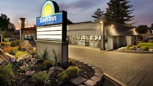 Un hotel Days Inn by Wyndham amb un cartell ben visible, una calçada asfaltada i una zona de jardí ben condicionada.