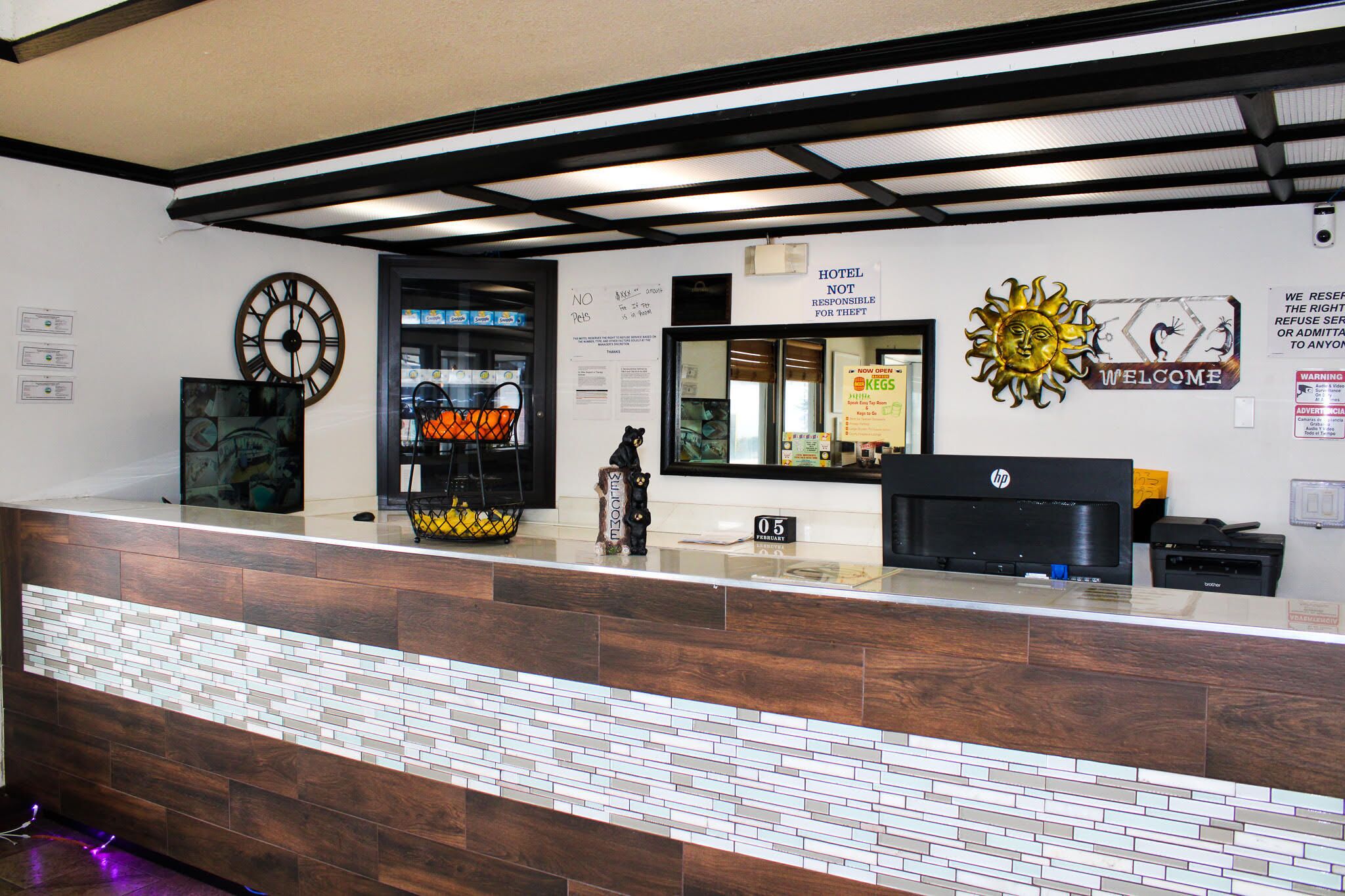 A hotel reception desk with a clock, a welcome sign, and a HP printer.