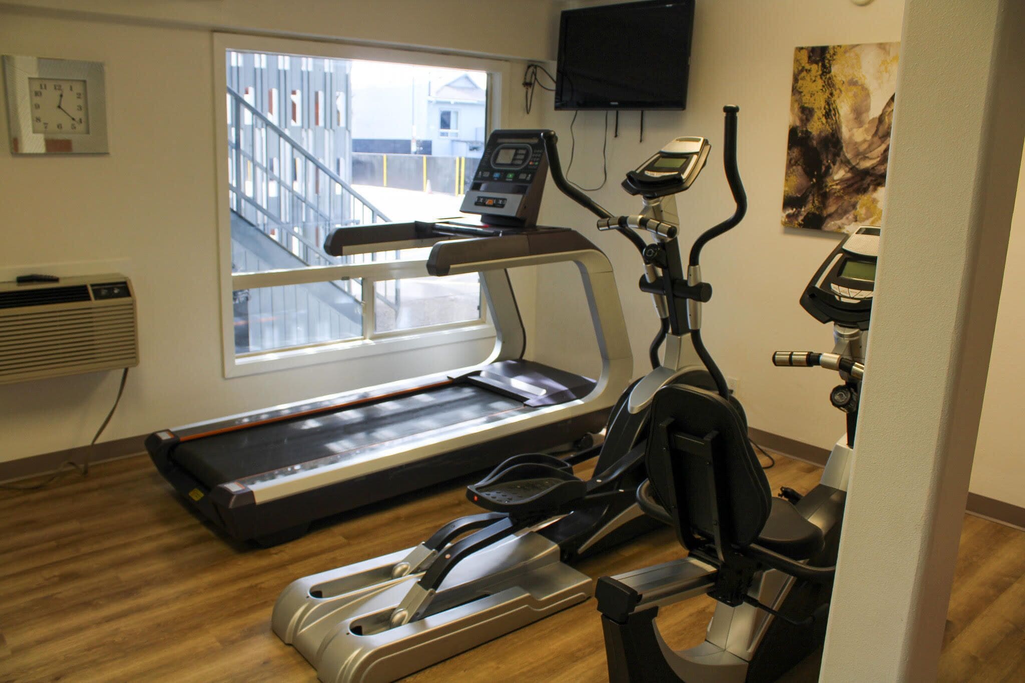 Une salle de sport équipée d’un tapis de course, d’un vélo elliptique et d’un vélo d’appartement.