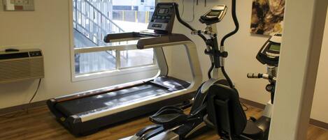 Une salle de sport équipée d’un tapis de course, d’un vélo elliptique et d’un vélo d’appartement.