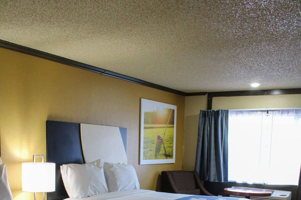 A hotel room with two beds, a desk, a chair, and a window with curtains.