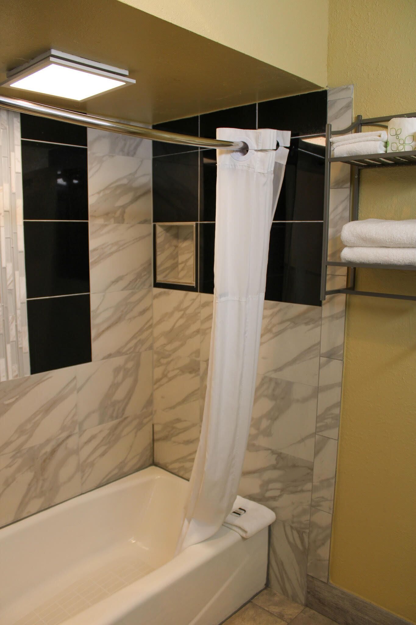 A bathroom with a bathtub, a shower curtain, and a towel rack.