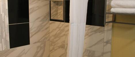 A bathroom with a bathtub, a shower curtain, and a towel rack.