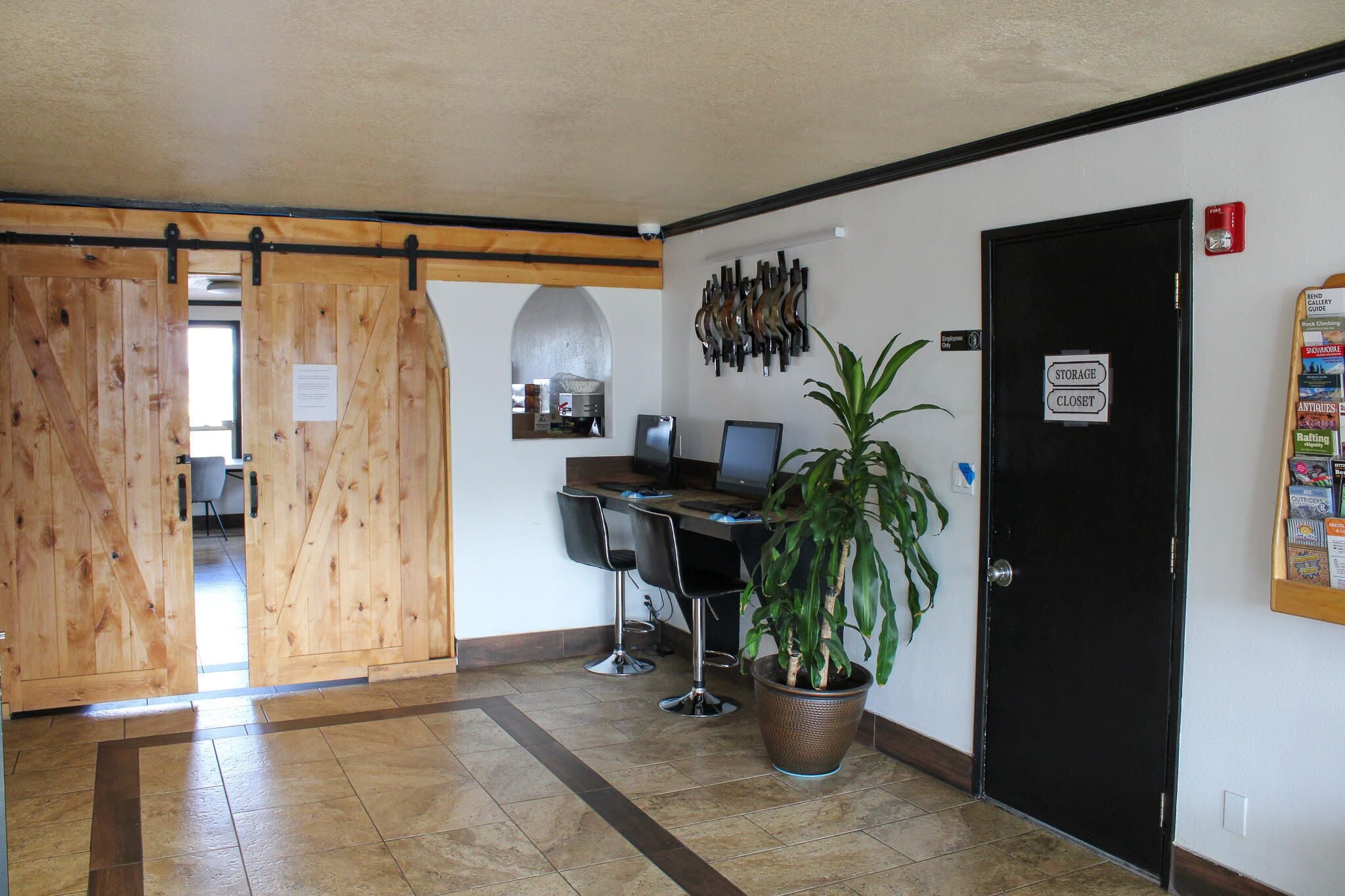 A reception area with a wooden sliding door, a desk with two chairs, a potted plant, and a black door with a storage closet sign.