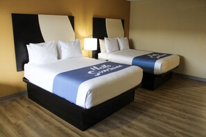 A hotel room with two beds, each with a headboard and a bedside table.
