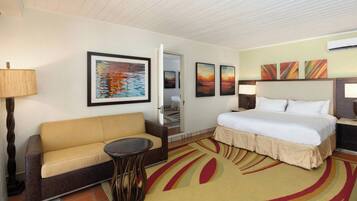 A hotel room with a bed, a sofa, a small table, and artwork on the walls.