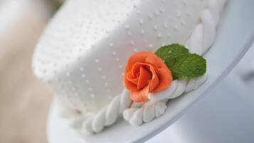A cake with a textured white surface and a single orange flower with green leaves.