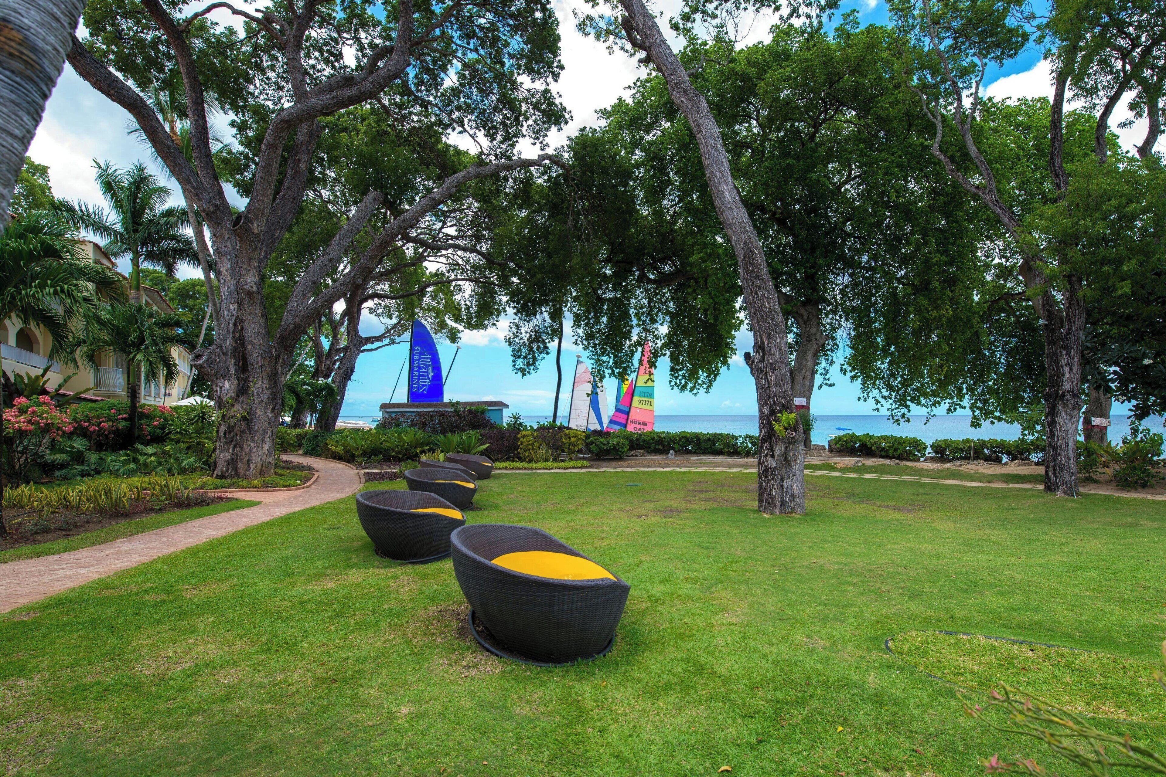 A landscaped outdoor area with a pathway, seating areas, and a view of the sea.