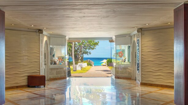 A spacious lobby with a polished floor, a view of the sea, and a pathway leading to outdoor seating. - Tamarind, Barbados, An Autograph Collection® All-Inclusive Resort (Paynes Bay)