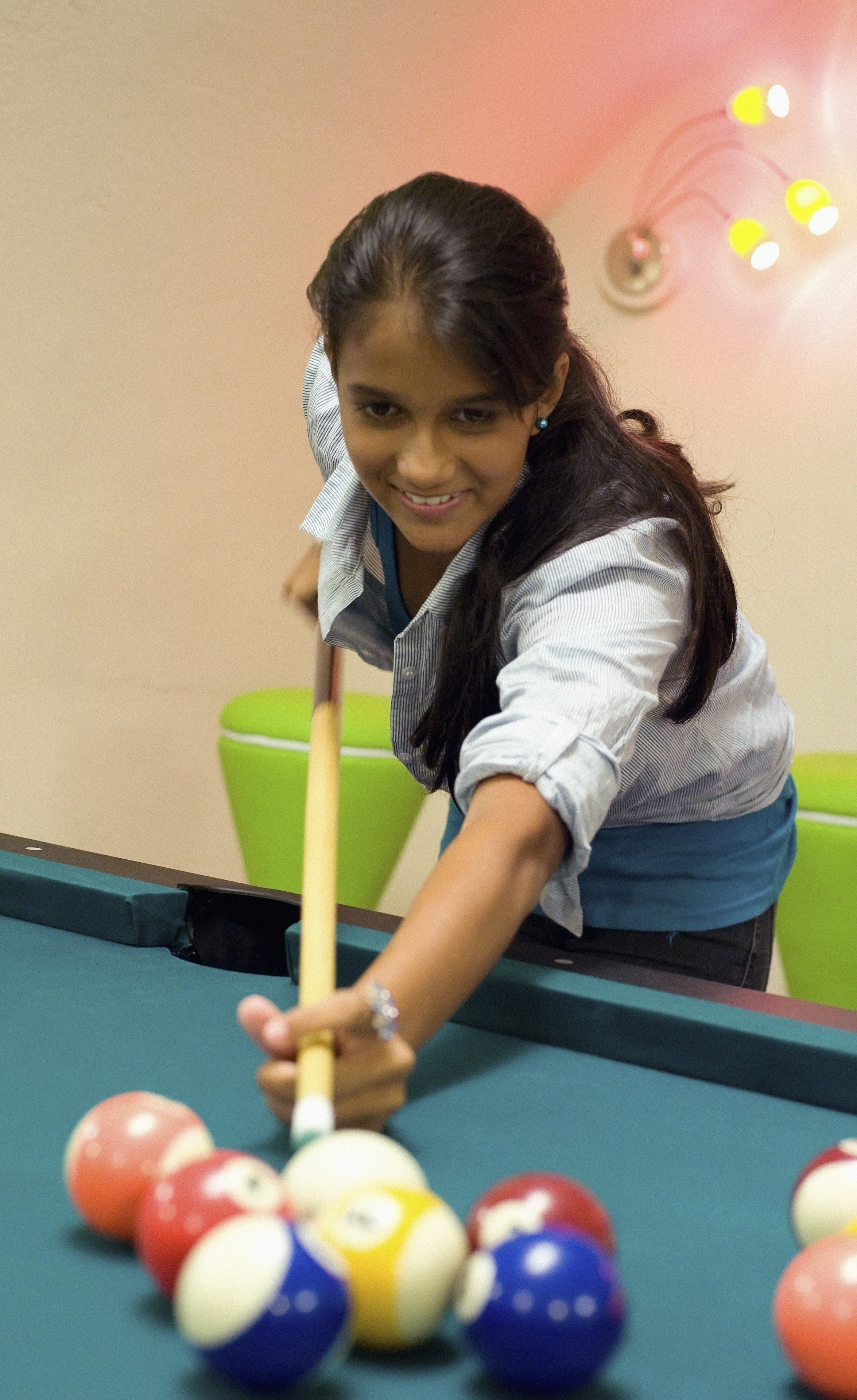 A person playing pool at a table with a green felt surface and colorful balls.