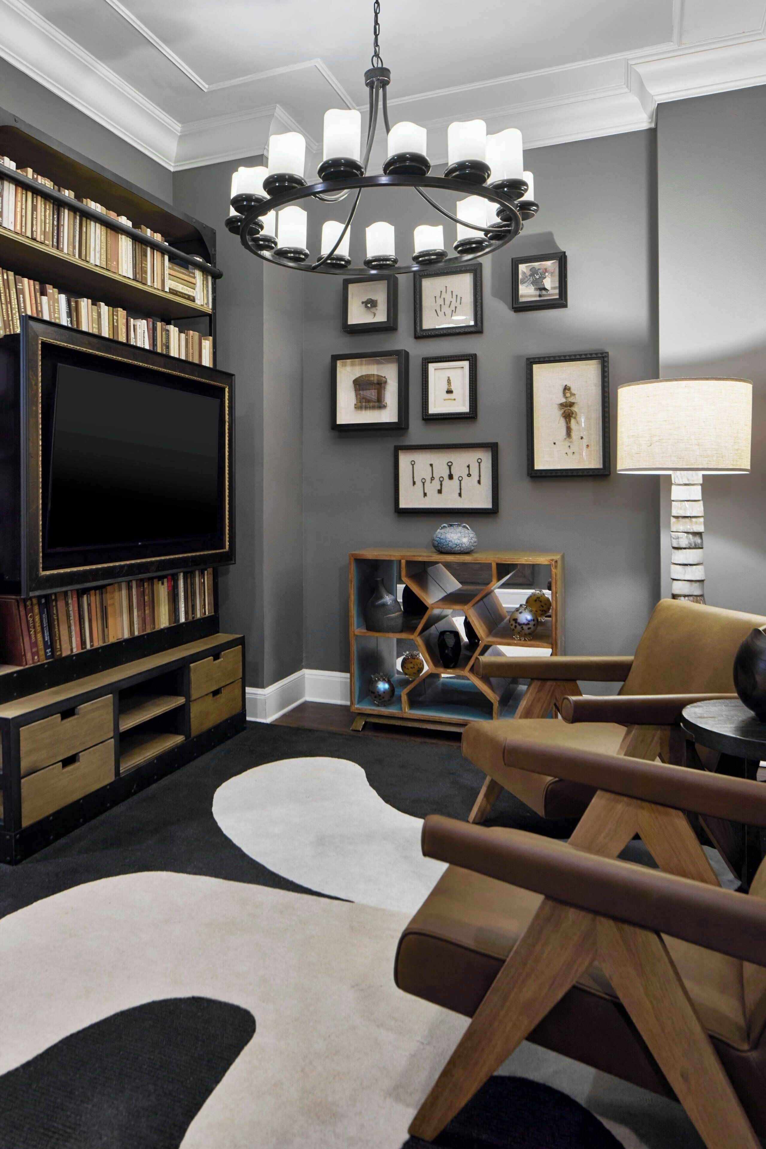 Un salon moderne doté d’un grand téléviseur à écran plat, d’un meuble de rangement en bois, d’un lustre, d’un fauteuil en cuir et d’un tapis à motifs.