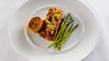 Un plato con pescado a la parrilla, espárragos y media limón asada.