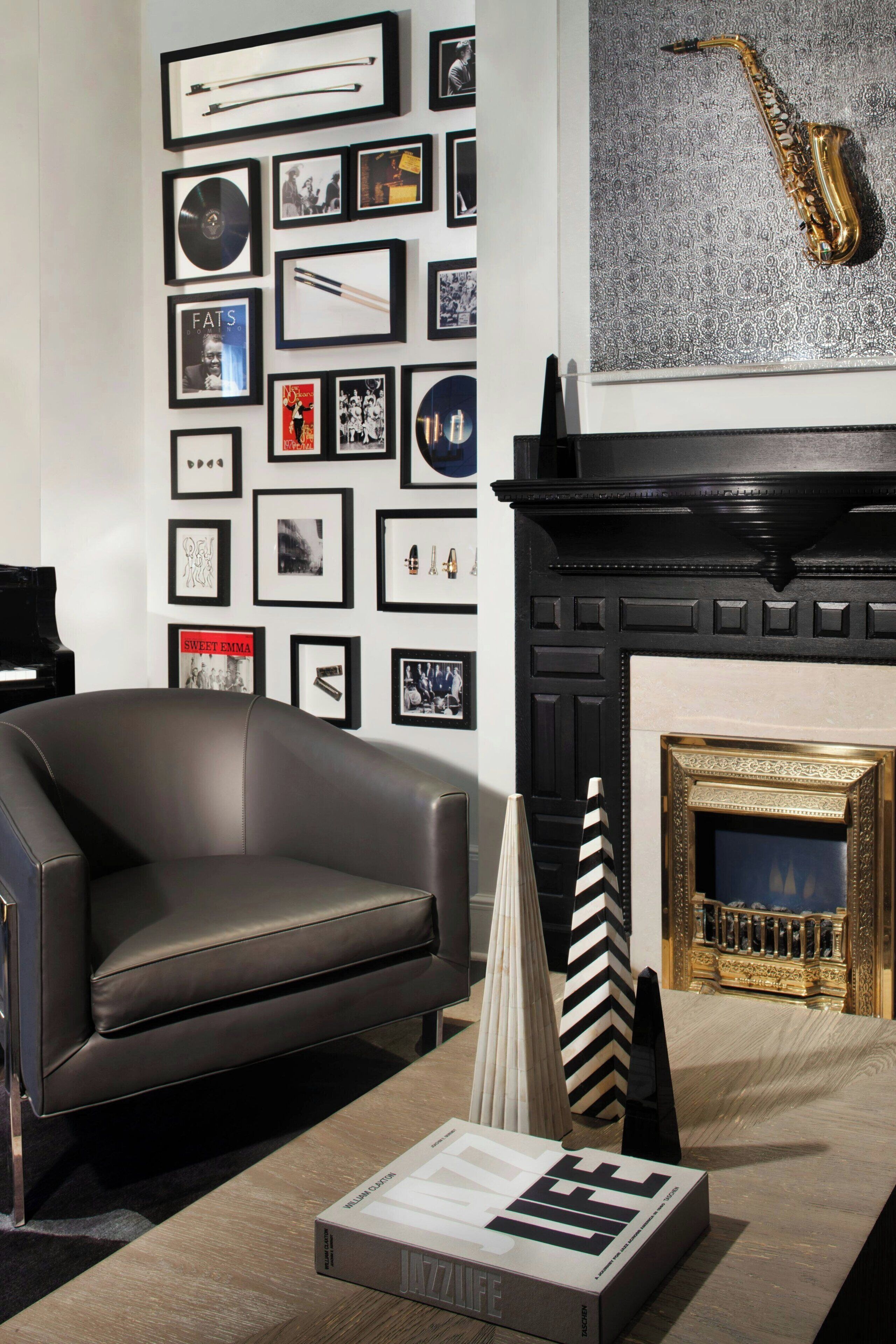 Una sala de estar moderna con un sofá de cuero, una chimenea y una pared decorada con cuadros y un saxofón.