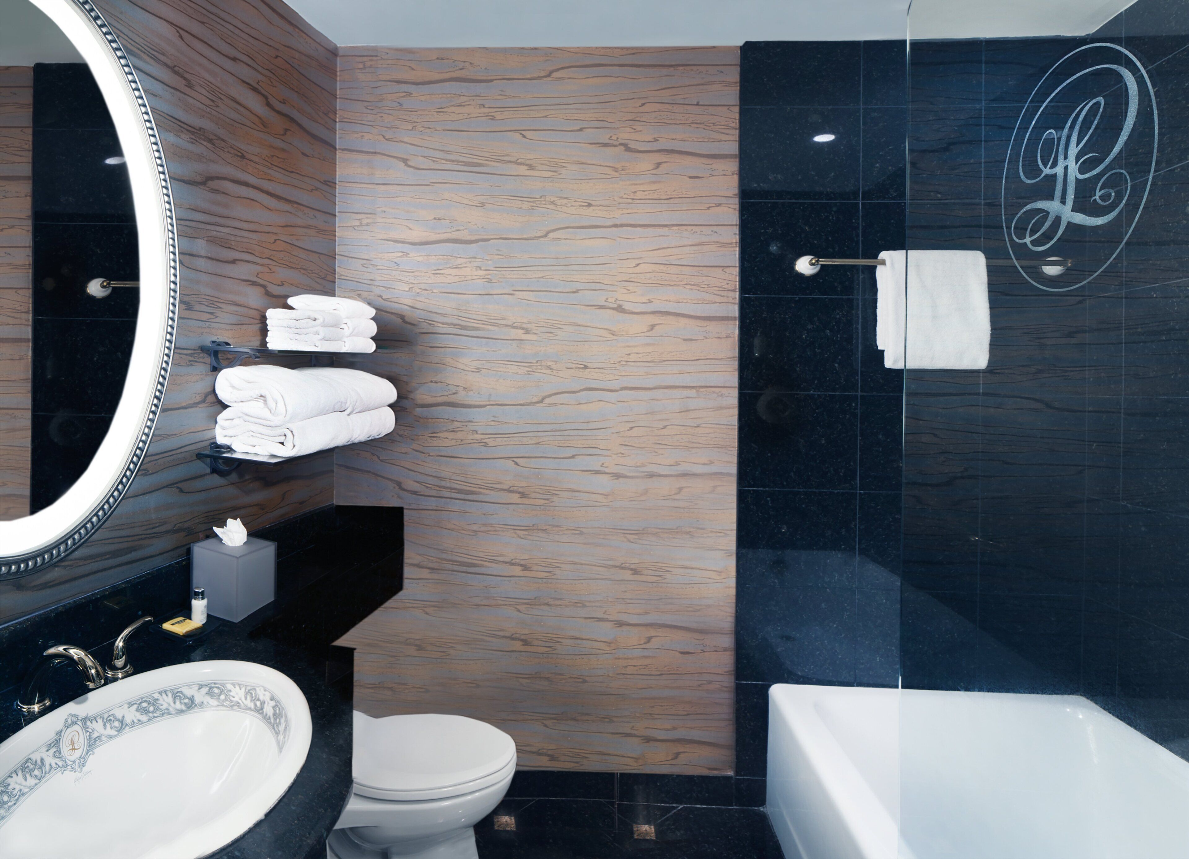 A modern bathroom with a wooden vanity, a large mirror, a white toilet, and a bathtub.