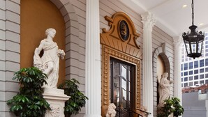 A grand entrance with a large arched doorway, flanked by white columns and statues. - Le Pavillon, New Orleans, a Tribute Portfolio Hotel by Marriott (New Orleans)