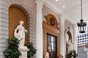 Una entrada imponente con un gran arco, flanqueado por columnas y estatuas blancas.