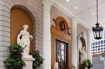 A spacious living room with a large chandelier, a fireplace, a sofa set, and a large painting on the wall. at Le Pavillon, New Orleans, a Tribute Portfolio Hotel by Marriott