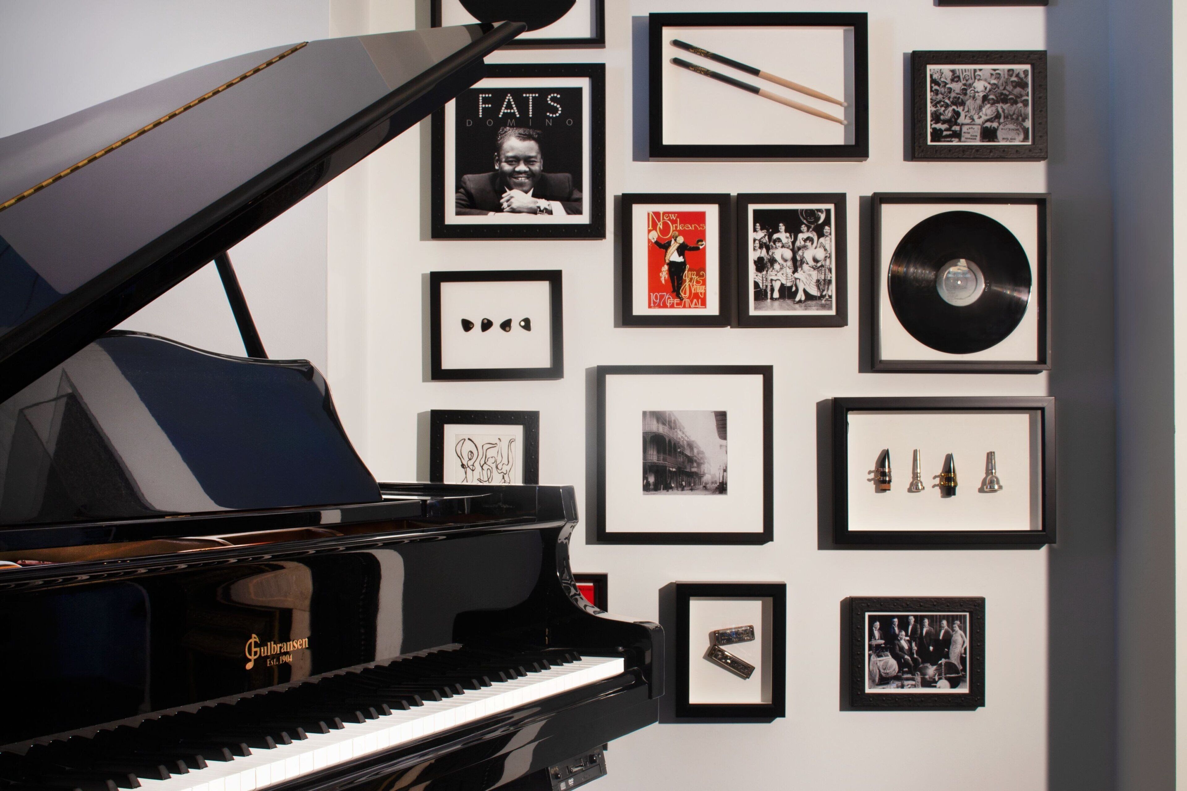 A grand piano in a room with a wall decorated with framed pictures and a vinyl record.
