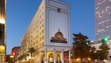 Ett hotell med en klassisk fasad, en framträdande entré med kolonner och en stor skylt som visar namnet ”Pavillon”.