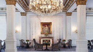 A grand lobby with a large chandelier, ornate columns, a fireplace, and seating arrangements. - Le Pavillon, New Orleans, a Tribute Portfolio Hotel by Marriott (New Orleans)