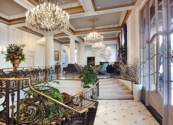 A grand entrance with a large arched doorway, flanked by white columns and statues. at Le Pavillon, New Orleans, a Tribute Portfolio Hotel by Marriott