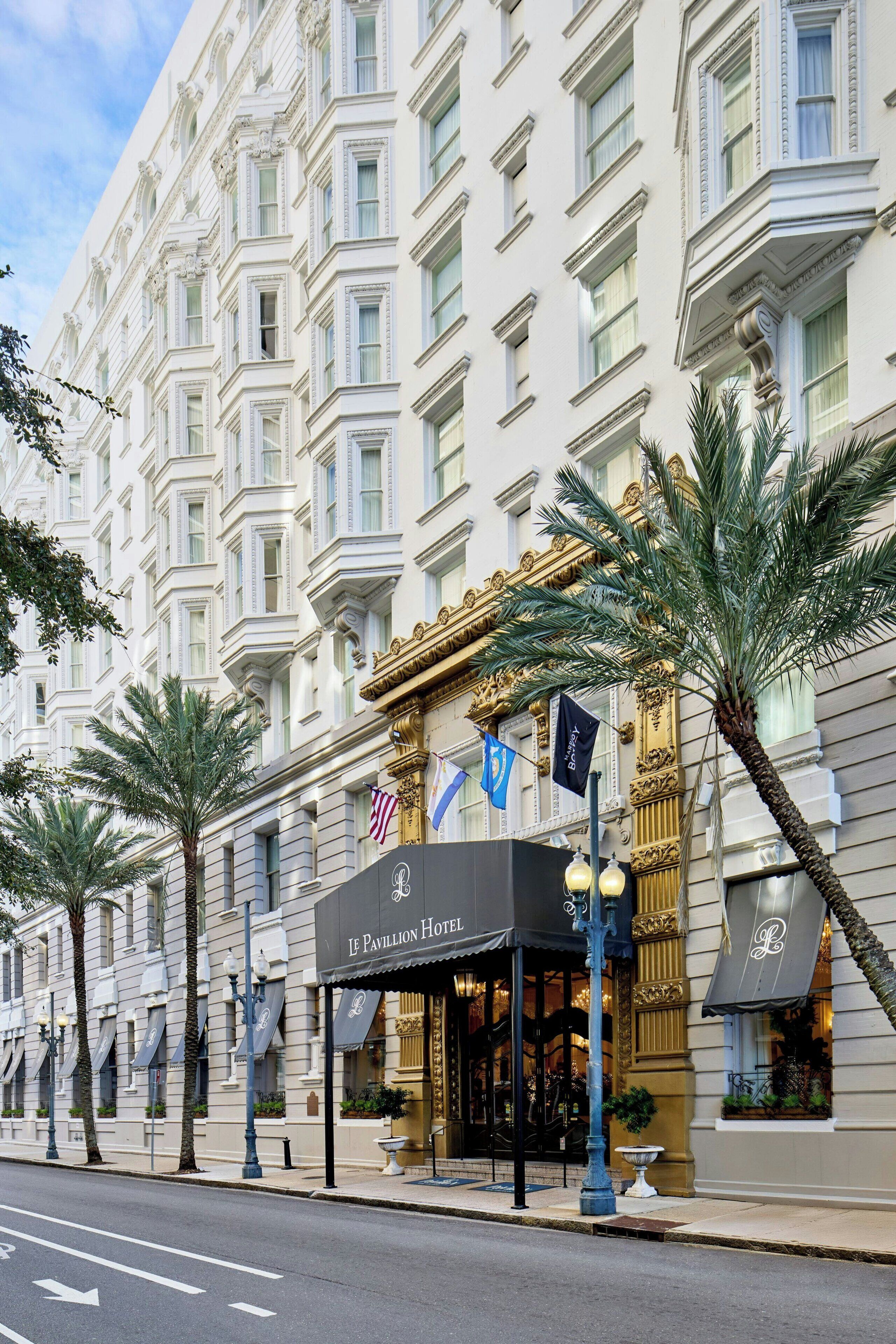 Fachada de hotel de estilo arquitectónico clásico, con diseño simétrico, ventanas amplias y una entrada destacada con toldo negro.