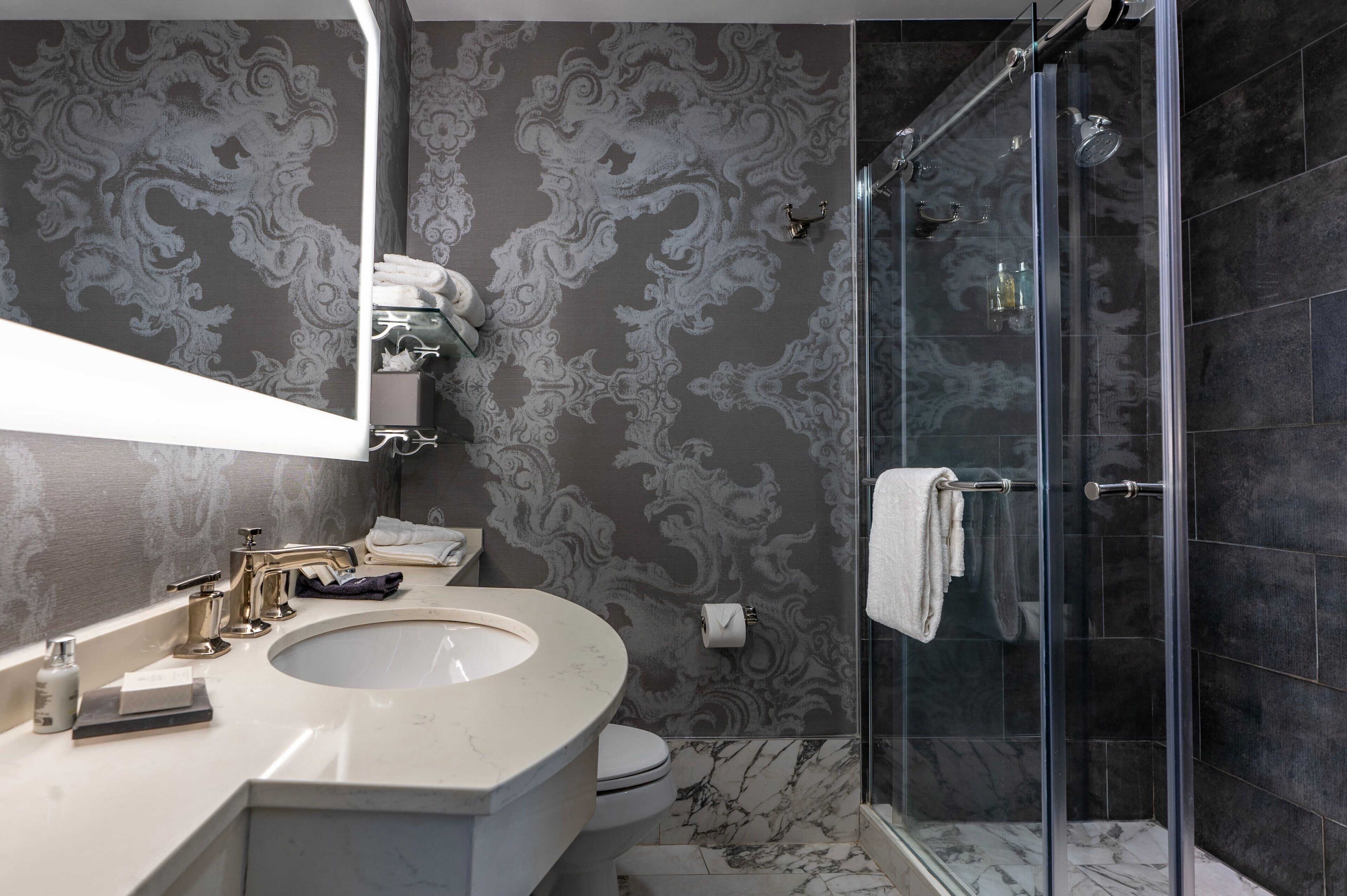 Ein Badezimmer mit Marmorwaschbecken, Toilette und einer Duschkabine.