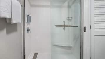 Un baño moderno con cabina de ducha de vidrio, una toalla blanca colgada en la pared y un pequeño estante con artículos de tocador.