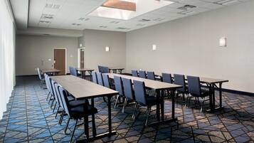 A conference room with a long table and chairs, a patterned floor, and a skylight.