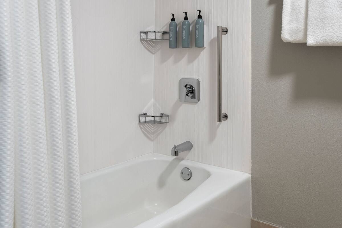 Ein Badezimmer mit einer weißen Badewanne, einer Dusche und einem Handtuchhalter.