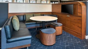 Un área de descanso moderna con un sofá modular, una mesa redonda y dos pufs.
