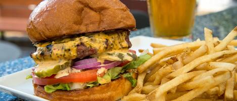 A burger with a side of fries and a glass of beer on a table.