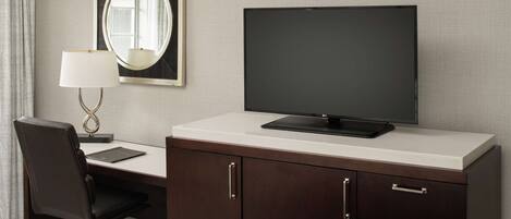 Une chambre d’hôtel équipée d’un bureau, d’une chaise, d’une télévision, d’un miroir et d’une lampe.