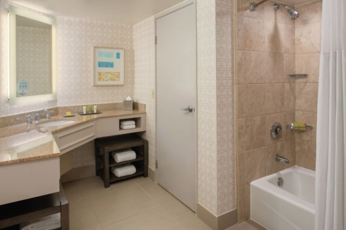 A modern bathroom with a sink, mirror, and shower.