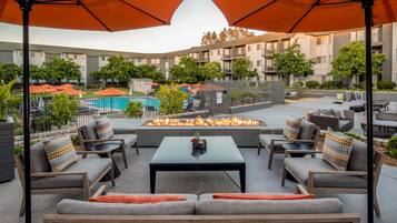 Relax in a serene setting with comfortable seating, a fire feature, and a pool view.