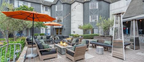 A courtyard with outdoor seating, fire pit, and string lights.