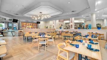 A modern restaurant with wooden tables and chairs, a bar area, and potted plants.