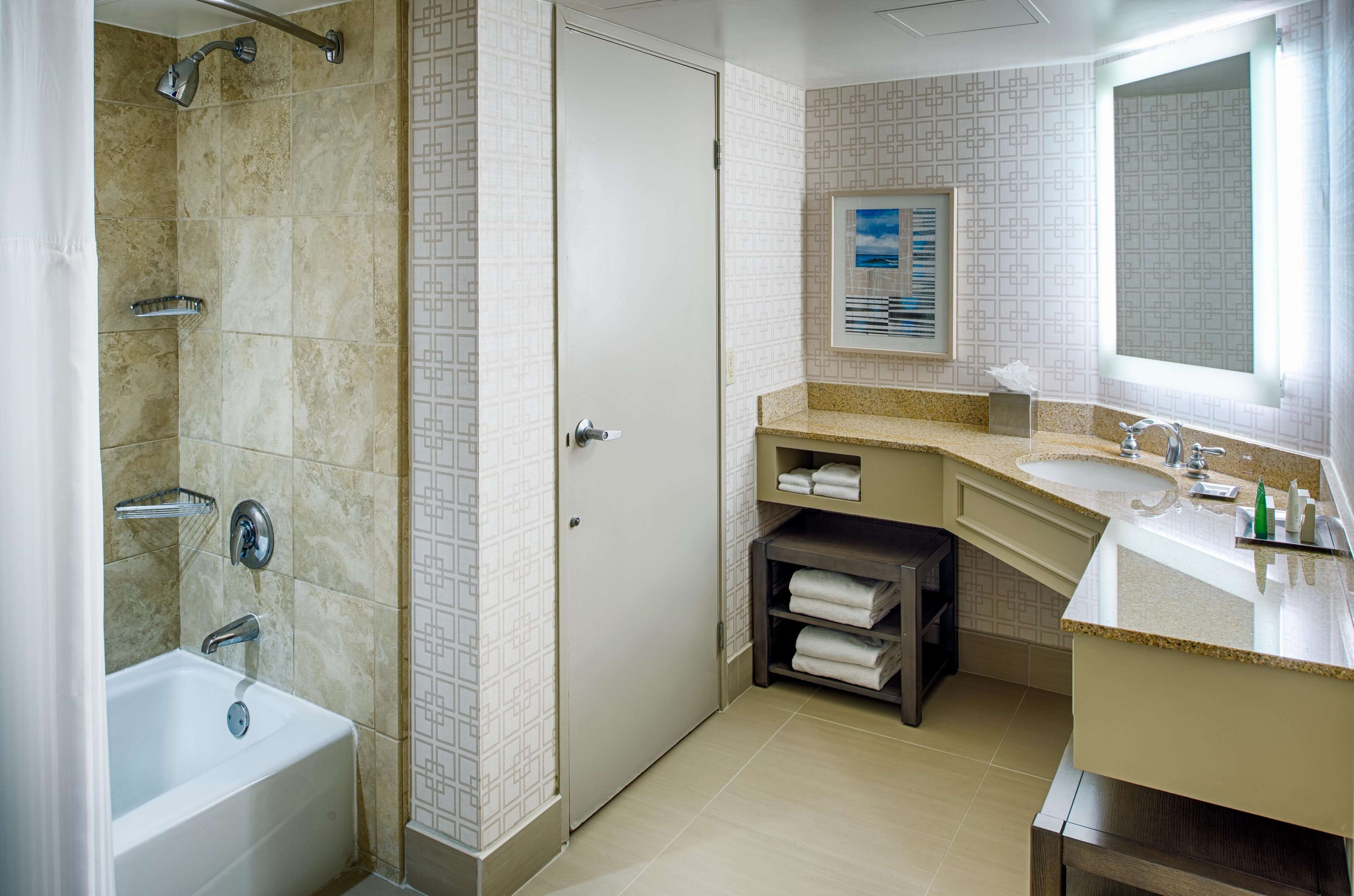 A modern bathroom with a bathtub, shower, vanity with a sink, and a mirror.