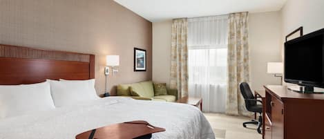 Una habitación de hotel con una cama, un escritorio, un televisor y una silla.