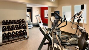 A gym with treadmills, elliptical machines, and a rack of dumbbells.