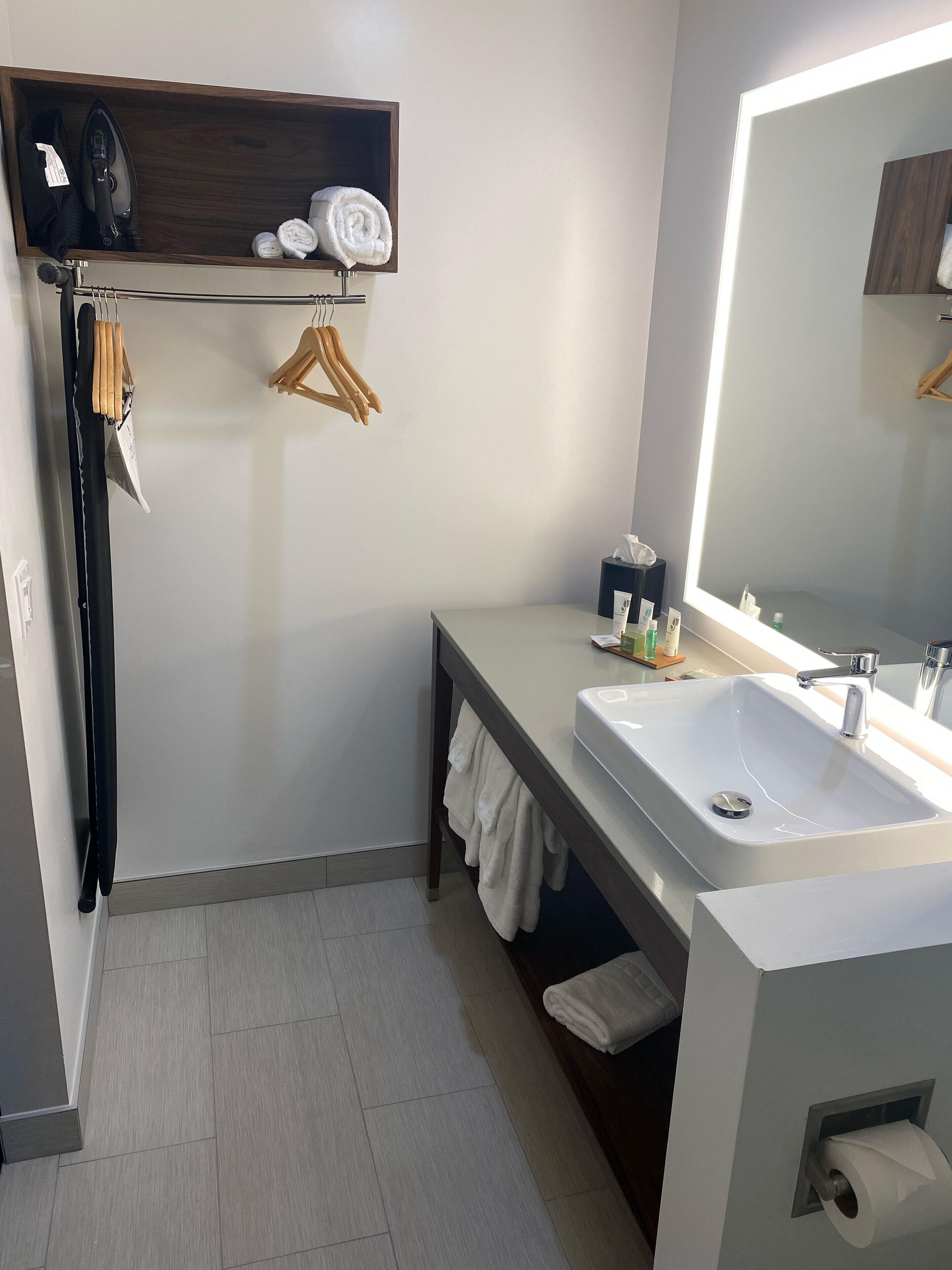 Un baño moderno con lavamanos integrado, un espejo y repisas con toallas y un secador de pelo.