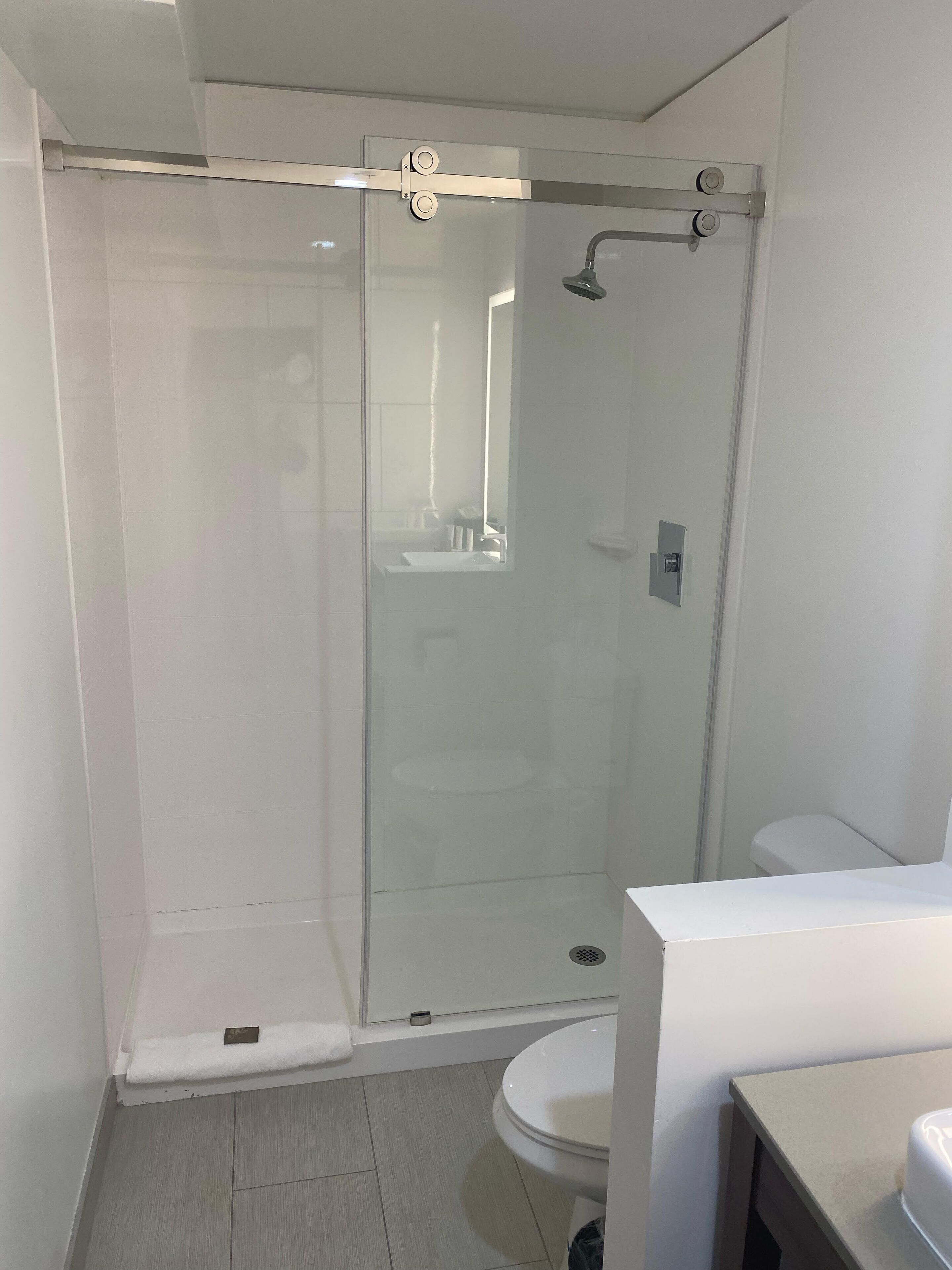 Een moderne badkamer met een douchecabine van glas, een wit toilet en een wastafel.