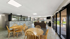 A spacious indoor area with a wooden dining table and chairs, a stone accent wall, and large windows offering views of the outdoors.