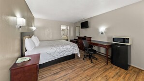 Une chambre d’hôtel équipée d’un lit, d’un bureau, d’une chaise et d’un petit réfrigérateur.